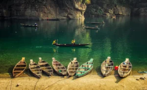 Boatmen rowing traditional wooden boats on the turquoise Dawki River in Meghalaya