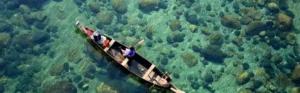 Aerial view of wooden boat floating on crystal-clear Umngot River at Dawki — most scenic Meghalaya tourist place